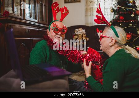 Seniorenpaar zu Hause mit einer Weihnachtsfeier auf einem Videoanruf Stockfoto