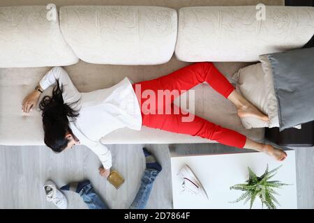 Frau liegt auf der Couch und hält eine Flasche Alkohol in der Hand. Stockfoto