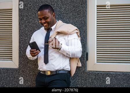 Porträt eines glücklichen afroamerikanischen Geschäftsmannes, der Smartphone benutzt. Stockfoto