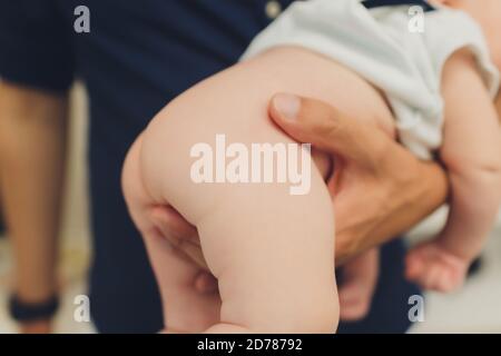 Mutter ändert die Windel eines kleinen Neugeborenen, während es auf dem Rücken auf einem Wickeltisch im Kinderzimmer liegt. Babyhygiene eine feuchte Serviette. Stockfoto