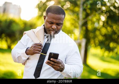 Porträt eines ernsthaften afroamerikanischen Geschäftsmannes, der Smartphone verwendet. Stockfoto