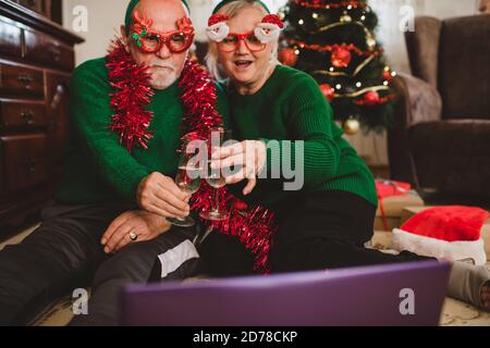 Seniorenpaar zu Hause mit einer Weihnachtsfeier auf einem Videoanruf Stockfoto