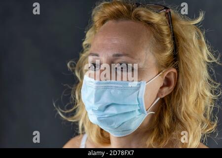 Porträt einer weißen Frau mittleren Alters, die weint, gezwungen, eine schützende Gesichtsmaske gegen das Risiko der Ansteckung von Covid-19 Coronavirus zu tragen Stockfoto