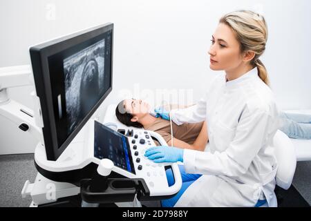 Eine Endokrinologin, die eine Patientin in einem Ultraschallbüro mit Ultraschall untersucht. Ultraschalldiagnostik der Schilddrüse. Stockfoto