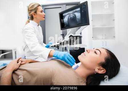 Eine Endokrinologin, die eine Patientin in einem Ultraschallbüro mit Ultraschall untersucht. Ultraschalldiagnostik der Schilddrüse. Stockfoto