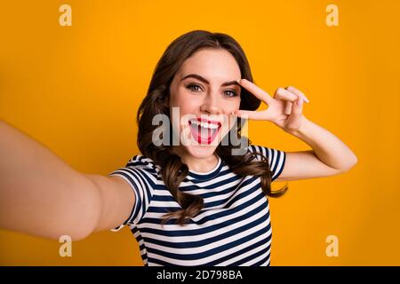 Foto von ziemlich lockig verrückt Millennial Dame rot hellen Lippenstift Machen Selfies zeigen V-Zeichen Symbol in der Nähe Auge tragen weiß lässig Gestreiftes T-Shirt Stockfoto