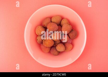 Mehrere Litschi-Früchte liegen auf einem Korallenteller Stockfoto