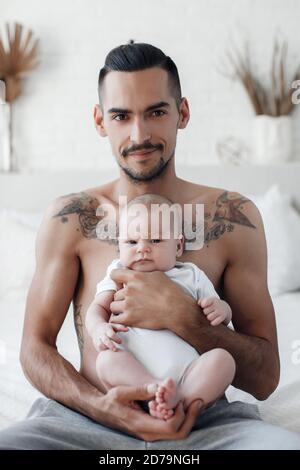 Mann mit Kleinkind. Glückliche Familie zu Hause. Glücklicher Vater mit niedlichen zwei Monate Baby Junge lag im hellen Bett zu Hause Stockfoto