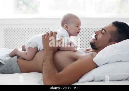 Mann mit Kleinkind. Glückliche Familie zu Hause. Glücklicher Vater mit niedlichen zwei Monate Baby Junge lag im hellen Bett zu Hause Stockfoto