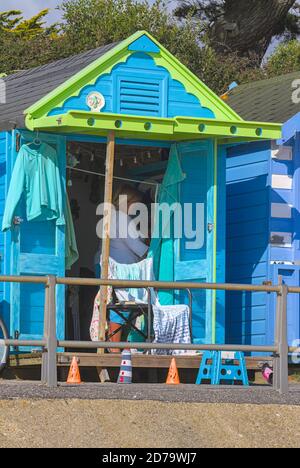 Dame macht Tee in EINEM bunten grünen und blauen Strand Hut am Avon Beach Christchurch Großbritannien Stockfoto