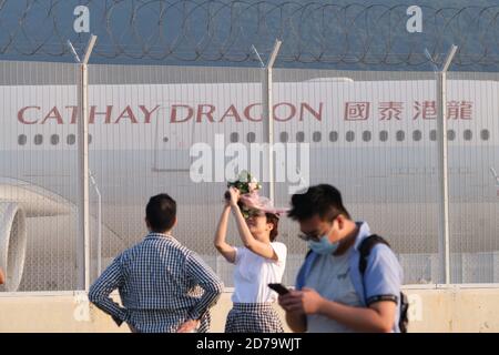 Menschen sind hinter einem Flugzeug zu sehen, das von Cathy Dragon, einer regionalen Linie von Cathay Pacific Airways Ltd., am Hong Kong International Airport betrieben wird. Cathay Pacific Group hat eine Umstrukturierung des Unternehmens als Reaktion auf die COVID-19-Krise angekündigt, die zu 8,500 Arbeitsplatzverlusten in der gesamten Gruppe und der Schließung von Cathay Dragon führen wird. Stockfoto