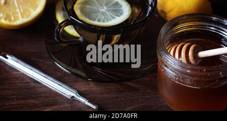 Drogen und Pillen auf einem Holztisch. Verschiedene Mittel, um Erkältungen zu verhindern. Tee mit Zitrone und Honig. Glas Tasse mit Tee Scheibe Zitrone und Glas Honig. Stockfoto