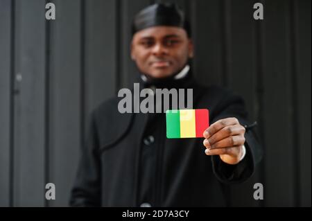 Afrikanischer Mann tragen schwarz durag halten Mali Flagge bei der Hand isoliert dunklen Hintergrund. Stockfoto
