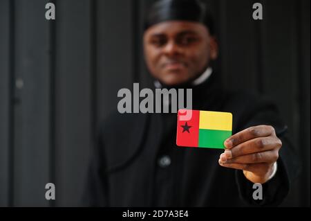 Afrikanischer Mann tragen schwarze durag halten Guinea-Bissau Flagge bei der Hand isoliert dunklen Hintergrund. Stockfoto