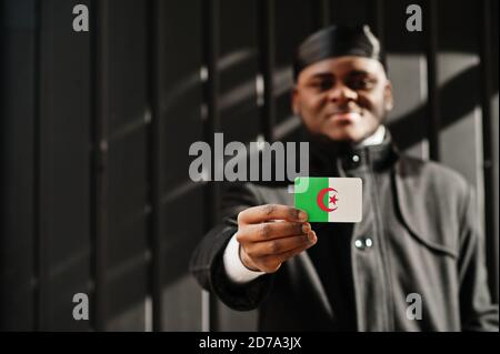 Afrikanischer Mann tragen schwarz durag halten Algerien Flagge bei der Hand isoliert dunklen Hintergrund. Stockfoto