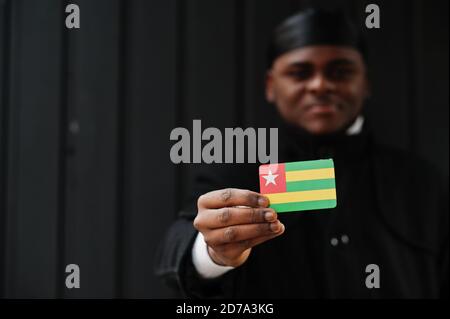 Afrikanischer Mann tragen schwarze durag halten Togo Flagge bei der Hand isoliert dunklen Hintergrund. Stockfoto