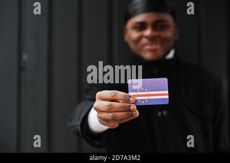 Afrikanischer Mann tragen schwarze durag halten Kap Verde Flagge bei der Hand isoliert dunklen Hintergrund. Stockfoto