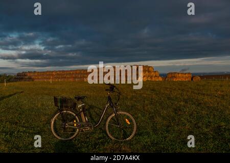 Heubälle und Elektrofahrrad auf dem Feld bei Ceske Budejovice Stadt in Sonnenaufgang Zeit in Farbe Herbst Stockfoto