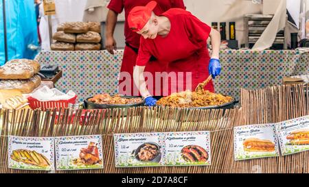 Stettin, Polen Jun 2019 Junge Köchin kocht ein traditionelles polnisches Essen namens Bigos in großer Pfanne auf dem Straßenmarkt oder fair. Tage des Meeres, Stettin Stockfoto