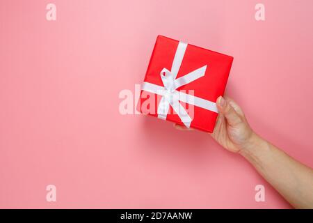 Flach Lay von Frau Hände halten Geschenk verpackt und mit Schleife isoliert auf rosa Hintergrund mit Kopie Raum dekoriert. Liebe zum Valentinstag. Geburtstagsmotiv. Stockfoto