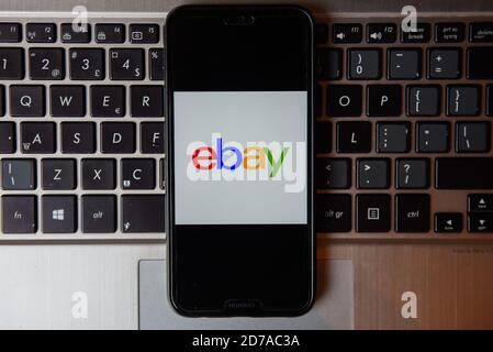 In dieser Abbildung ist ein eBay-Logo auf einem Smartphone mit einer Laptop-Tastatur im Hintergrund zu sehen. Stockfoto