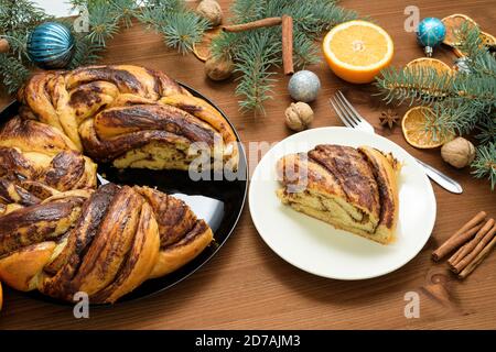 Schokoladen-Weihnachtsgroßmutter in Form eines Kranzes mit Orangensirup auf einem in Stücke geschnittenen Teller. Weihnachtsschmuck auf einem Holztisch. Stockfoto