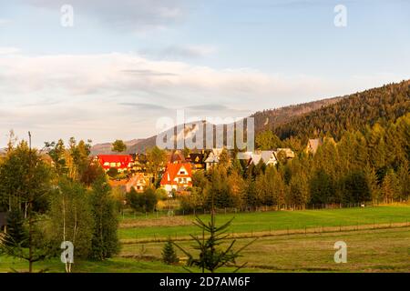 Traditionelle polnische Highlander-Stil Häuser in Krzeptowki, Zakopane, Tatra Berge, während des Sonnenuntergangs, unter grünen Pinien auf einem Berghang. Stockfoto