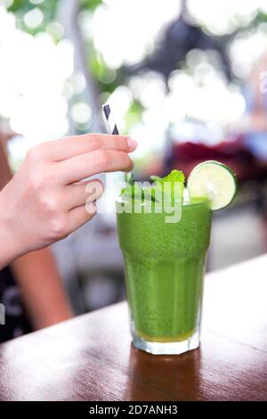 Grüner veganer gesunder Smoothie mit Minze in Glas in weiblichen Händen. Sauberes Detox Essen. Gewichtsverlust Konzept Stockfoto