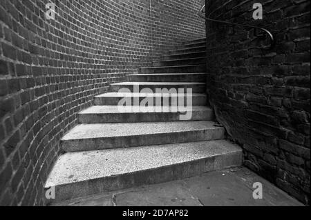 Schwarz-weiß monochromes Bild von Blick auf einige verwinkelte Straßentreppen nach rechts in einer Gasse. Stockfoto