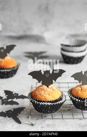 Halloween Kürbis Muffins in schwarzen Kapseln mit Karton Fledermäuse verziert. Festliche Halloween Cupcakes. Nahaufnahme des köstlichen gruseligen halloween Muf Stockfoto