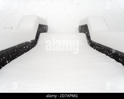 Die Stufen sind mit einer gleichmäßigen Schneeschicht übersät An einem nebligen Tag bei starkem Schneefall Stockfoto