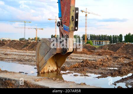 Bagger Schaufel auf der Baustelle bei Sonnenuntergang Hintergrund und auf den blauen Himmel. Flurbereinigung, Sortierung, Pool, Aushub, Grabenaushub, utilit Stockfoto