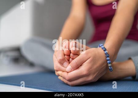 Yoga Stretching Frau auf Übungsmatte zu Hause. Sitzende Schmetterling Bein strecken hält Sohlen der Füße zusammen mit den Händen Stockfoto