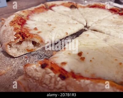 Hausgemachte Margherita-Pizza in Scheiben geschnitten auf einem bemehlten Holzbrett Stockfoto