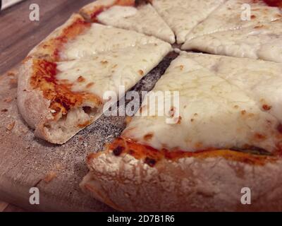 Hausgemachte Margherita-Pizza in Scheiben geschnitten auf einem bemehlten Holzbrett Stockfoto