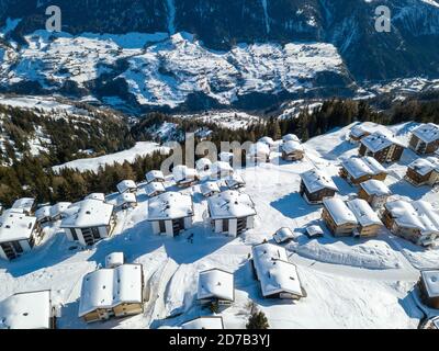 Luftaufnahme von verschneiten Dächern über den traditionellen Chalets mit Skilift-Station im Dorf Schweizer alpen. Stockfoto