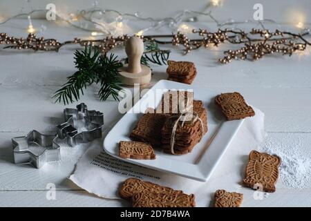 Weihnachtsstimmung, Spekuloos mit Spekuloos gestapelt gebunden mit einem Verpackungsband, wunderschön auf einem weißen Porzellanteller auf einem weißen Holztisch dekoriert, i Stockfoto