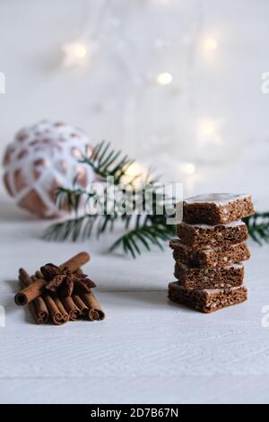 Advent- und Weihnachtsstimmung, Honigkuchen gestapelt, wunderschön dekoriert auf einem weißen Holztisch im Hintergrund eine weiße weihnachtskugel und Licht Stockfoto