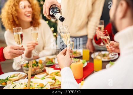 Mann gießt Getränk aus der Flasche zu glücklichen Freunden Stockfoto