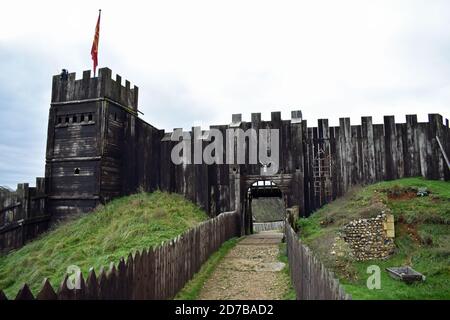 Ein Weg führt zu den hölzernen Burgmauern und dem Turm Mit roter Flagge bei der authentischen Rekonstruktion von Stansted Mountfitchet Castle in Essex, England Stockfoto