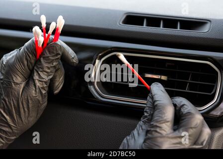 Arbeiter reinigen den Entlüftungsgrill der Auto-Klimaanlage mit Bürste, in der Nähe. Autowaschanlage Stockfoto