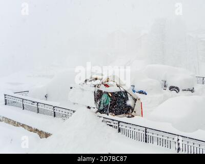 Schneepflug Traktor und andere Fahrzeuge stark mit Schnee bedeckt Auf einem Parkplatz während eines Schneesturms Stockfoto