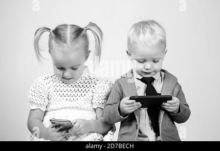 Kinder mobil süchtig. Kleines Paar mit Telefon. Junge und Mädchen schüchtern auf Datum online. Liebe, Freundschaft Konzept. Valentinstag. Sozialkonzept. Stockfoto