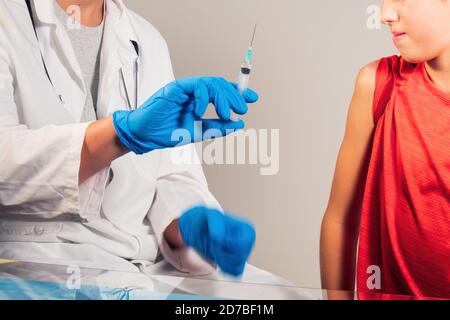 Arzt impfen Kind für Coronavirus in der Klinik. Spritze mit Handschuhen geschützte Hände. Stockfoto