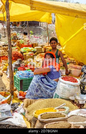 Stallhalter an einem Stand, der Chilis, Gewürze und lokale Produkte in einem Straßenmarkt in einem Dorf im Madhya Pradesh, Indien, verkauft Stockfoto