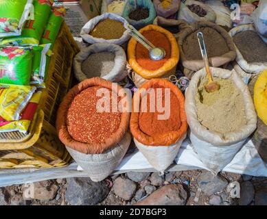 Säcke mit bunten Gewürzen, Linsen und Hülsenfrüchten an einem Stand, der lokale Produkte auf einem Straßenmarkt in einem Dorf in Madhya Pradesh, Indien, verkauft Stockfoto