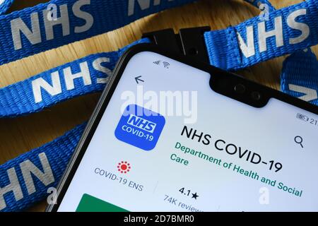 Manchester / Großbritannien - 21. Oktober 2020: NHS COVID-19 App im Play Store auf dem Bildschirm des Smartphones neben dem NHS-Trageband. Stockfoto
