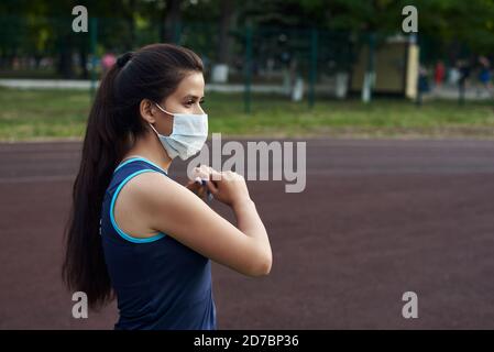 Ein junges Mädchen geht in einer Schutzmaske auf die Straße zum Sport. Sport in Quarantäne, Coronavirus, covid-19 Konzept. Stockfoto