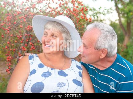 Authentische Außenaufnahme des alternden Paares, das Spaß im Garten hat und mit Liebe gesegnet ist. Während ihres Spiels Mann versucht, seinen Partner zu küssen und sie ist Stockfoto