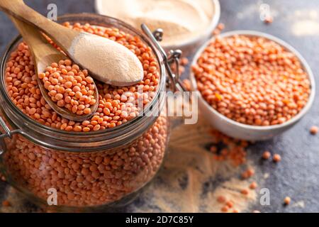 Rote Linsen und Linsenmehl in den Holzlöffeln über einer Schüssel rote Linsen. Stockfoto